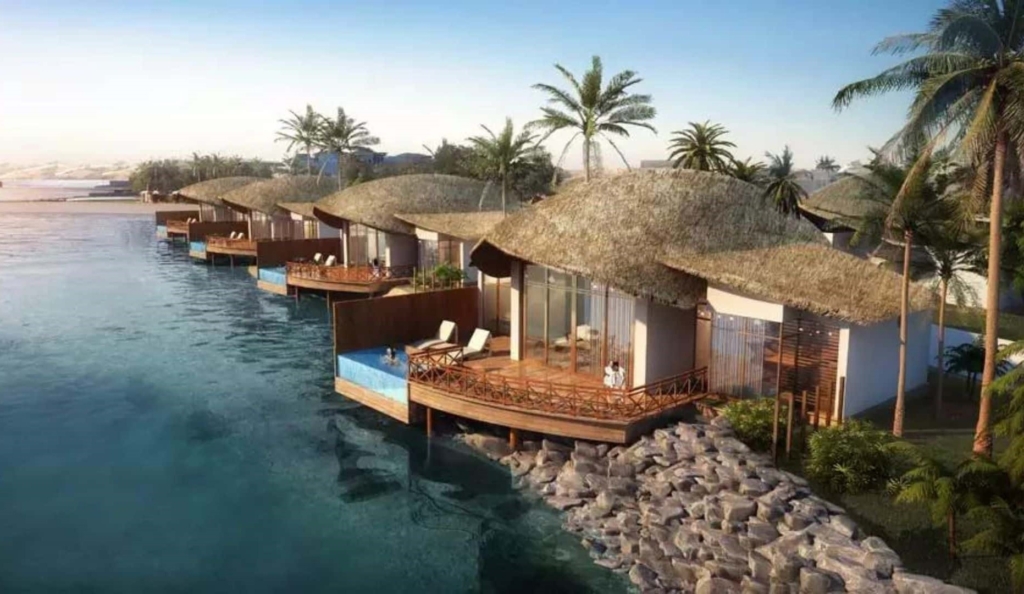 Luxury overwater villas with thatched roofs in Ras Al Khaimah, featuring private decks, infinity pools, and stunning ocean views, surrounded by palm trees and serene waters.