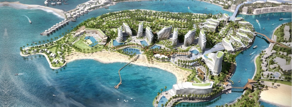 An aerial view of a luxurious island development in Ras Al Khaimah, featuring modern waterfront residences, lush greenery, sandy beaches, and a marina.